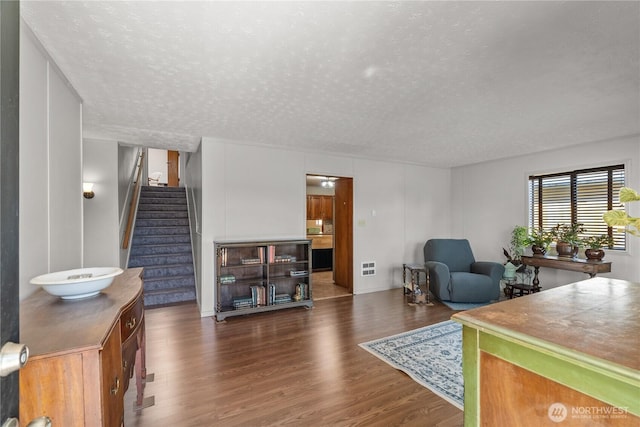 living room with wood finished floors, stairway, a textured ceiling, and baseboards