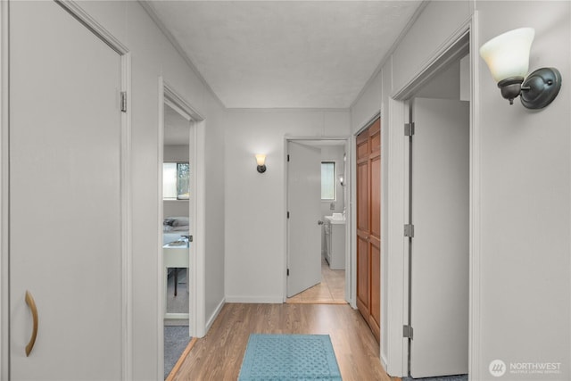 corridor with light wood finished floors, healthy amount of natural light, and baseboards