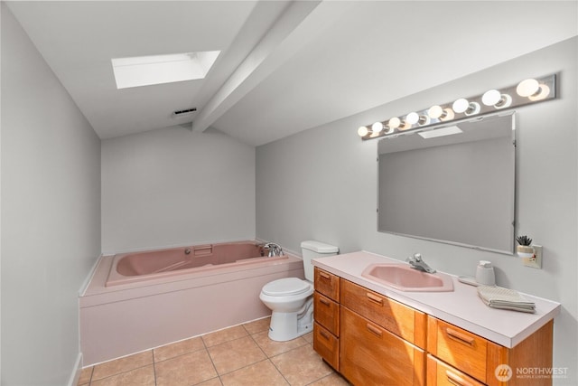 bathroom featuring a skylight, tile patterned flooring, a garden tub, vanity, and toilet