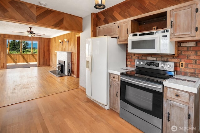 25443 Pioneer Way NW, Poulsbo, WA 98370 - kitchen with white appliances, tile countertops, wood walls, light wood-style floors, and ceiling fan
