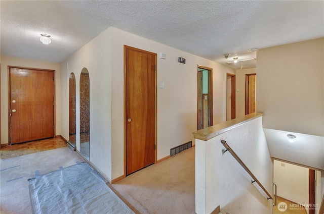 2734 Sunset Dr W, University Place, WA 98466 - hall with light colored carpet, a textured ceiling, an upstairs landing, visible vents, and arched walkways