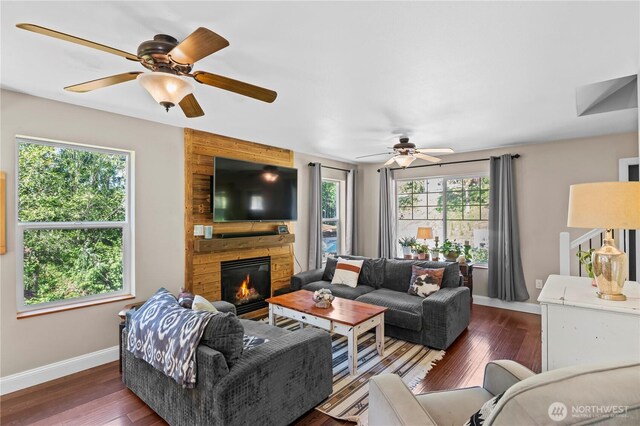 living area with baseboards, a fireplace, ceiling fan, and wood finished floors