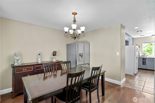 dining space featuring a chandelier, baseboards, and wood finished floors