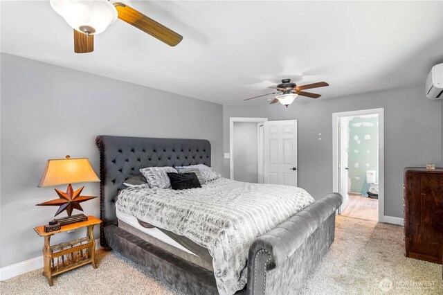 carpeted bedroom featuring baseboards, ceiling fan, an AC wall unit, and ensuite bathroom