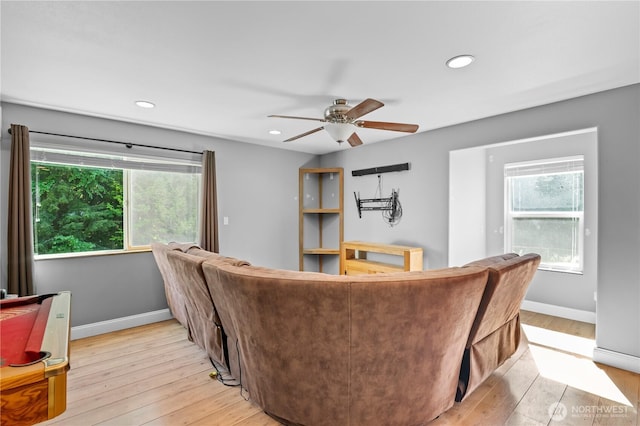 living area featuring healthy amount of natural light, a ceiling fan, light wood finished floors, recessed lighting, and baseboards