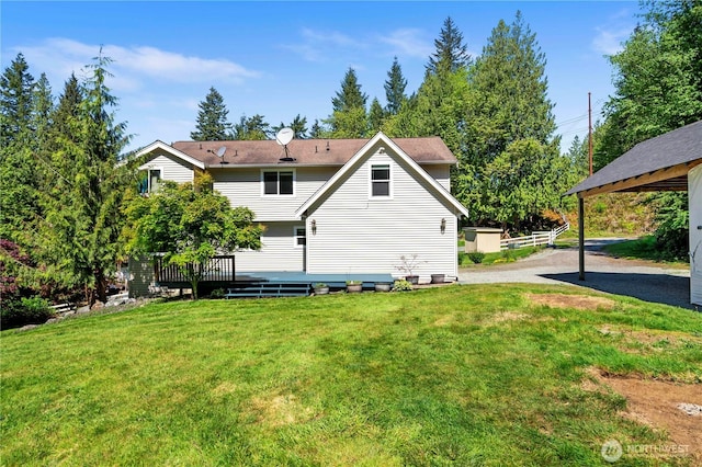 rear view of house featuring a wooden deck and a yard