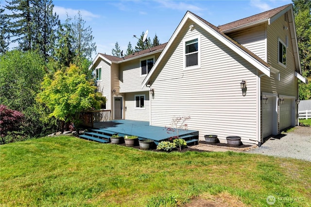 rear view of house with a deck, a lawn, a garage, and driveway