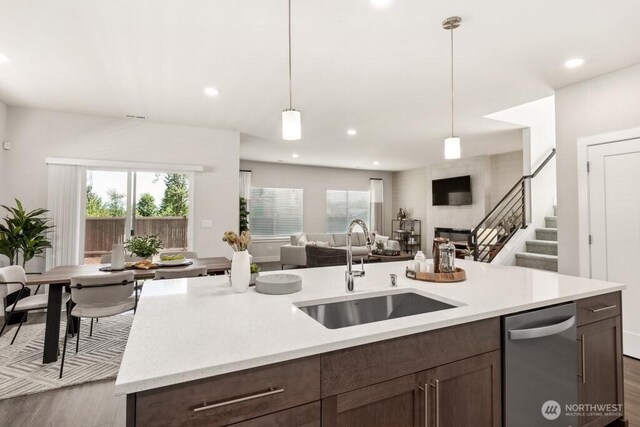 kitchen with hanging light fixtures, dark brown cabinets, open floor plan, and a sink