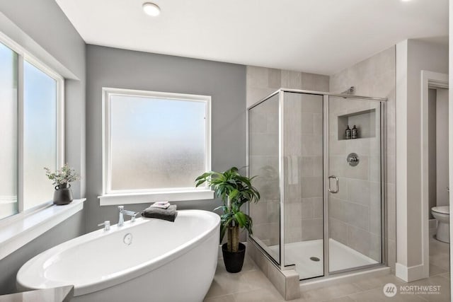 bathroom with a soaking tub, toilet, tile patterned flooring, and a stall shower