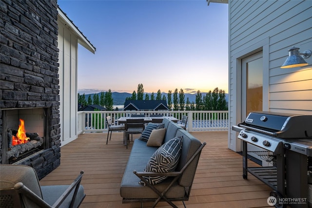 deck featuring grilling area, an outdoor stone fireplace, and a mountain view