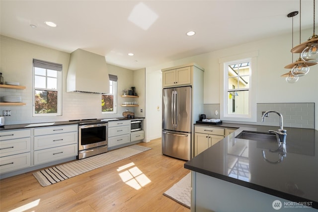 kitchen featuring stainless steel appliances, open shelves, custom range hood, dark countertops, and a sink