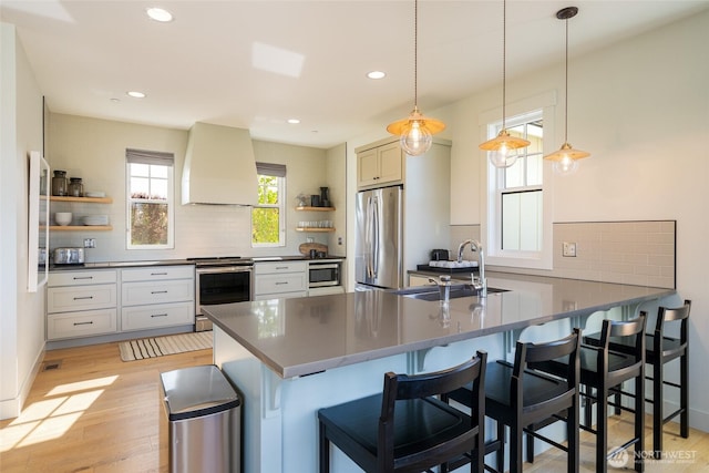 kitchen featuring appliances with stainless steel finishes, open shelves, a sink, premium range hood, and recessed lighting