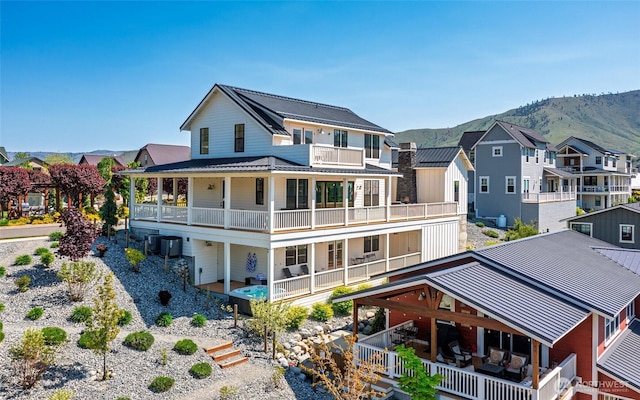 rear view of property with a balcony, metal roof, a mountain view, a standing seam roof, and a residential view