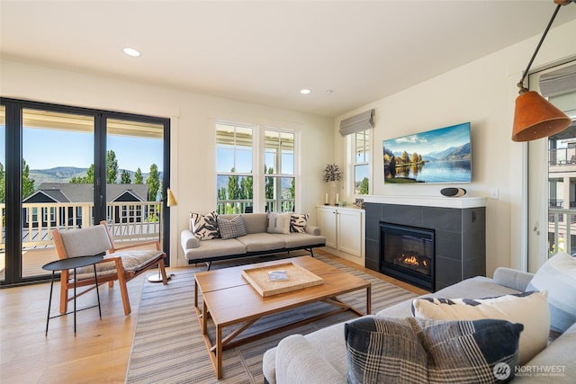 living room featuring healthy amount of natural light, a fireplace, light wood-style flooring, recessed lighting, and a mountain view