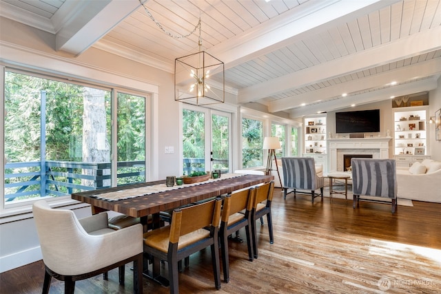 dining space featuring beamed ceiling, a chandelier, wood ceiling, a fireplace, and wood finished floors