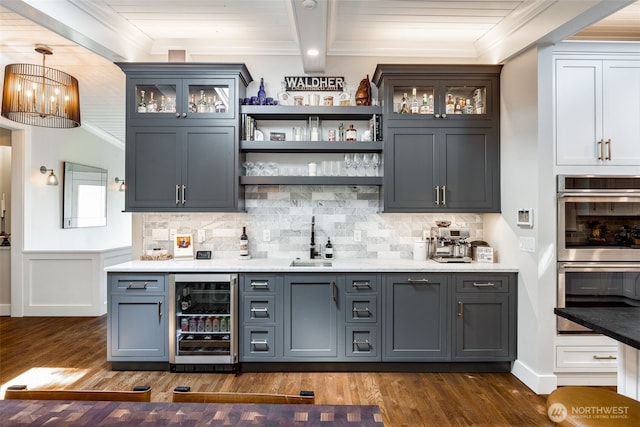 indoor wet bar featuring beverage cooler, double oven, crown molding, dark wood-style flooring, and tasteful backsplash