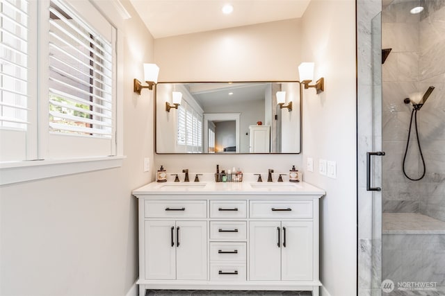 bathroom featuring tiled shower, double vanity, and baseboards