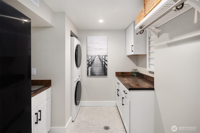 laundry room featuring stacked washing machine and dryer, baseboards, recessed lighting, and light tile patterned floors