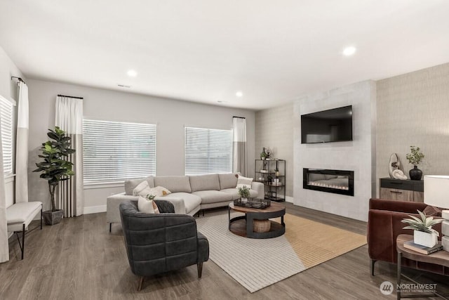 living room with a large fireplace, recessed lighting, baseboards, and wood finished floors