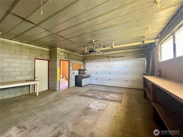 garage featuring a garage door opener, a workshop area, and concrete block wall