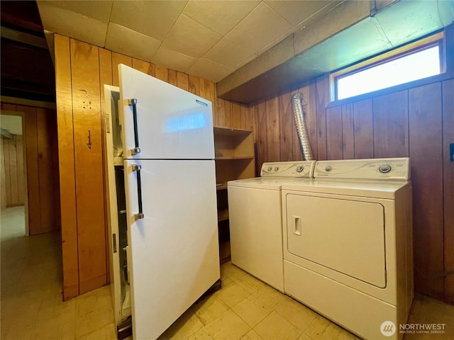 laundry area with wooden walls and washing machine and dryer