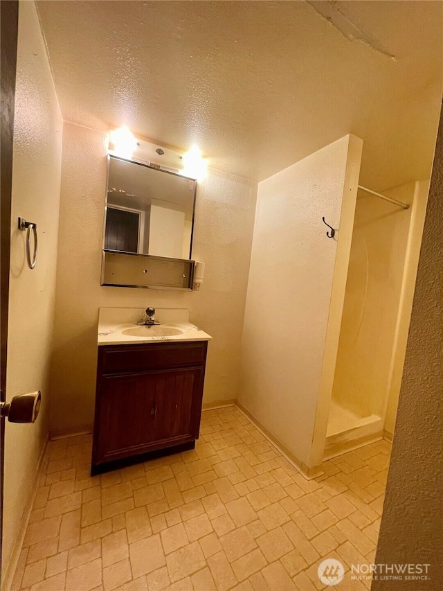 full bathroom with a shower, vanity, brick patterned floors, and a textured ceiling