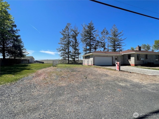 view of home's exterior with an attached garage, fence, dirt driveway, and a chimney