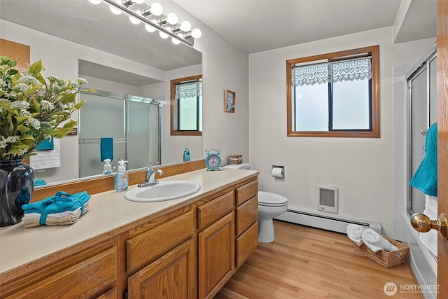 565 Olympic View Ln, Camano Island, WA 98282 - bathroom with baseboard heating, a shower with shower door, toilet, vanity, and wood finished floors