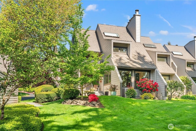 view of front of property with a shingled roof, a chimney, and a front yard