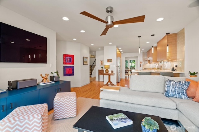 living room featuring stairway, light wood-style flooring, ceiling fan, and recessed lighting