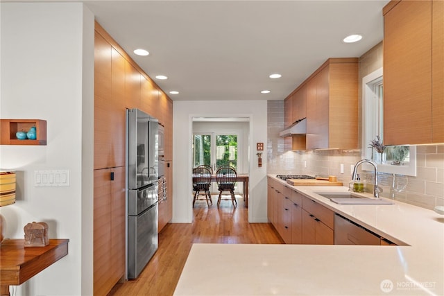 kitchen with a sink, stainless steel appliances, recessed lighting, backsplash, and light wood-style floors