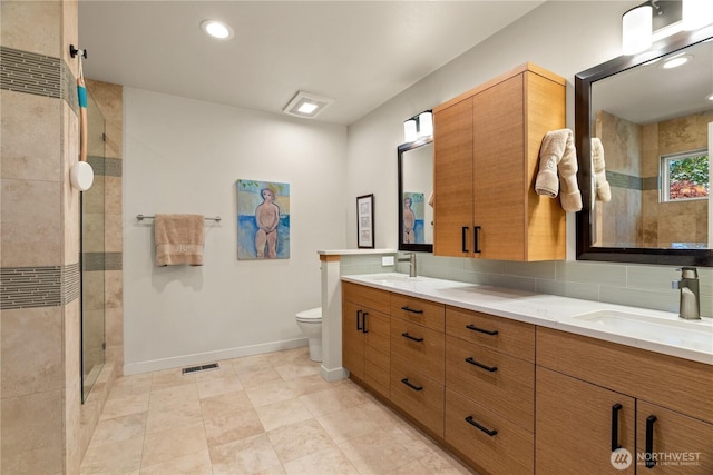 full bath featuring toilet, visible vents, a tile shower, and a sink