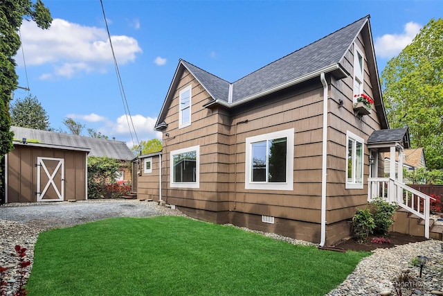 view of side of home featuring a shed, a lawn, an outdoor structure, crawl space, and a shingled roof