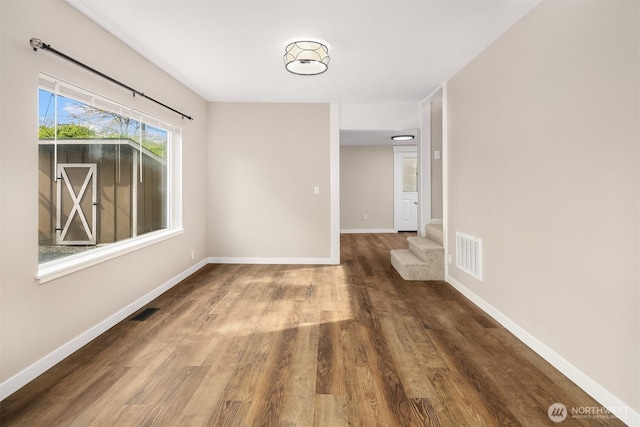 spare room featuring wood finished floors, baseboards, and stairs
