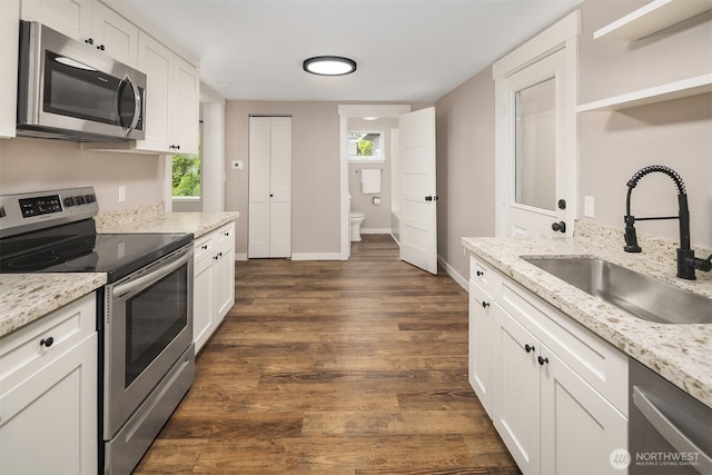 kitchen featuring stainless steel appliances, a sink, white cabinetry, and dark wood-type flooring