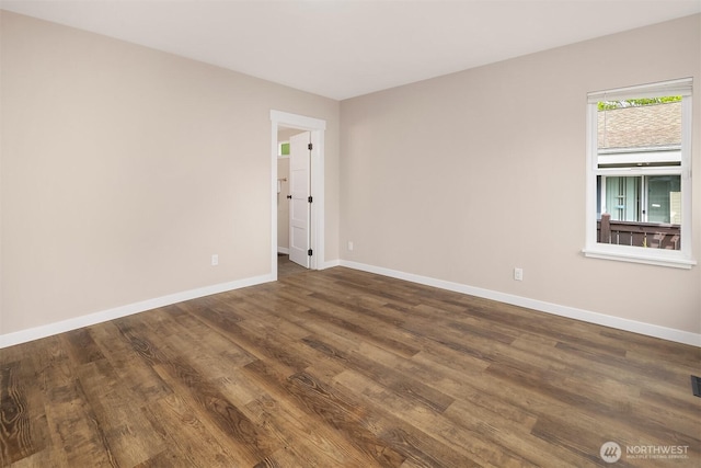 spare room with dark wood-style floors and baseboards