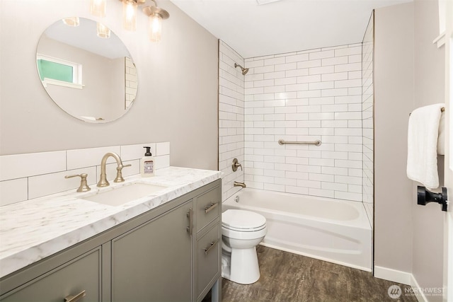 bathroom with toilet, wood finished floors, vanity, and shower / bathtub combination