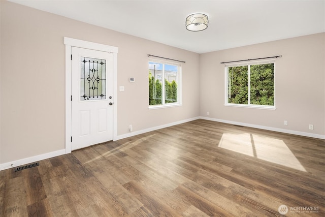 foyer entrance with healthy amount of natural light, wood finished floors, and baseboards