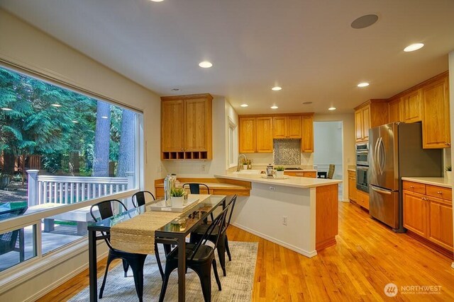 kitchen featuring a peninsula, light countertops, appliances with stainless steel finishes, a sink, and recessed lighting