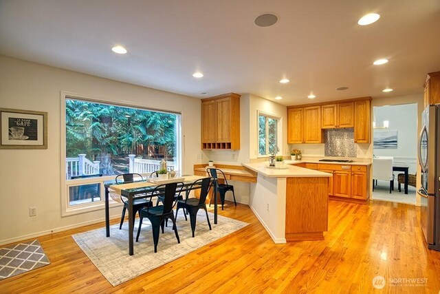 kitchen featuring a peninsula, freestanding refrigerator, light countertops, light wood-style flooring, and recessed lighting