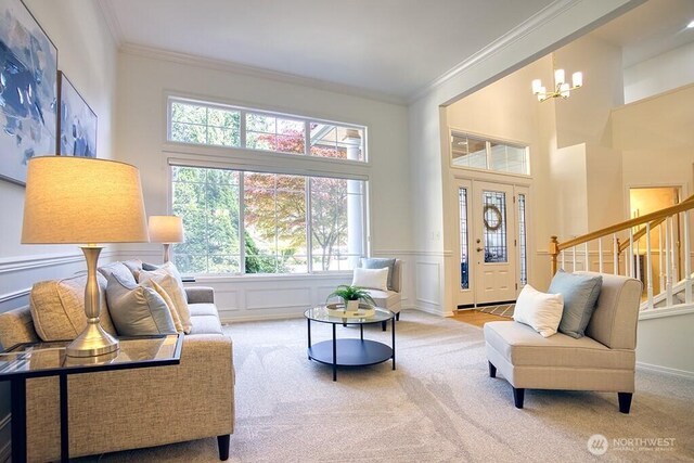 sitting room featuring carpet flooring, ornamental molding, stairs, a chandelier, and wainscoting