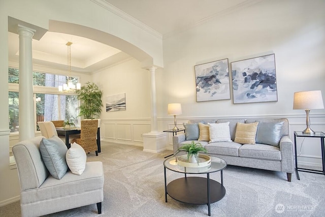 carpeted living area with decorative columns, arched walkways, ornamental molding, a decorative wall, and a chandelier