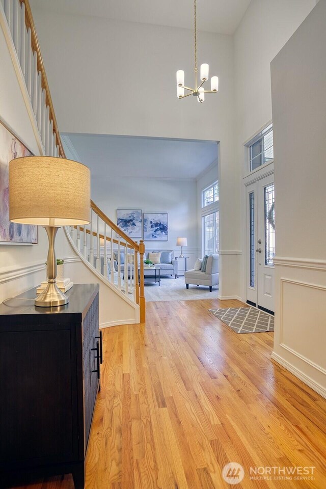 entrance foyer featuring stairs, a high ceiling, a chandelier, and light wood finished floors