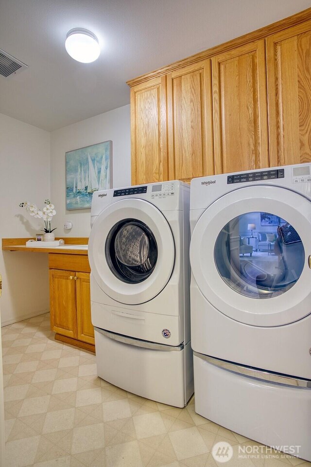laundry room featuring washer and dryer, cabinet space, and light floors