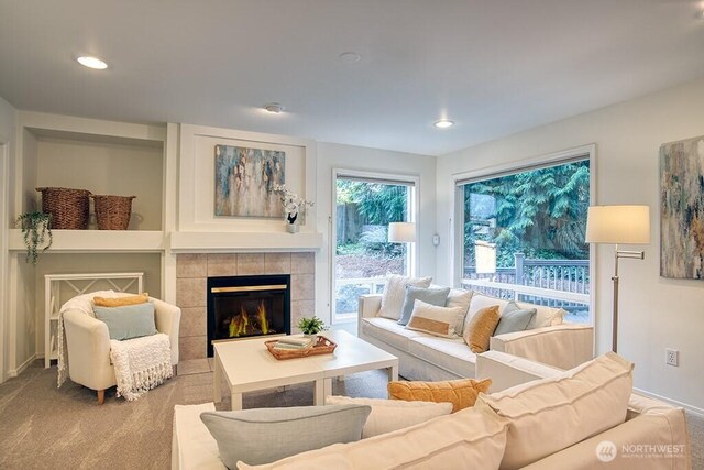 carpeted living area with a tiled fireplace, baseboards, and recessed lighting