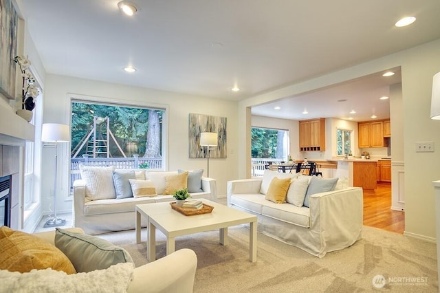 living area featuring a glass covered fireplace, recessed lighting, and light carpet