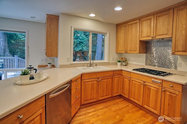 kitchen featuring a sink, stainless steel dishwasher, gas cooktop, light wood-style flooring, and brown cabinets
