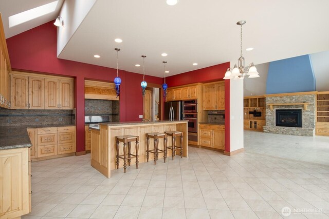 kitchen featuring tasteful backsplash, a skylight, a stone fireplace, a breakfast bar, and a center island