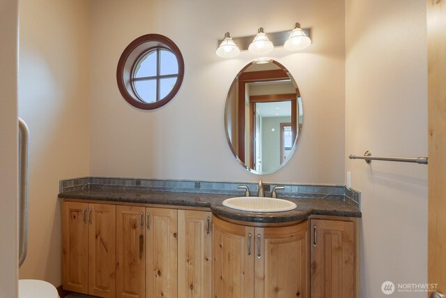 half bathroom with vanity and toilet