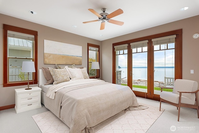 bedroom featuring a water view, light carpet, access to outside, multiple windows, and recessed lighting